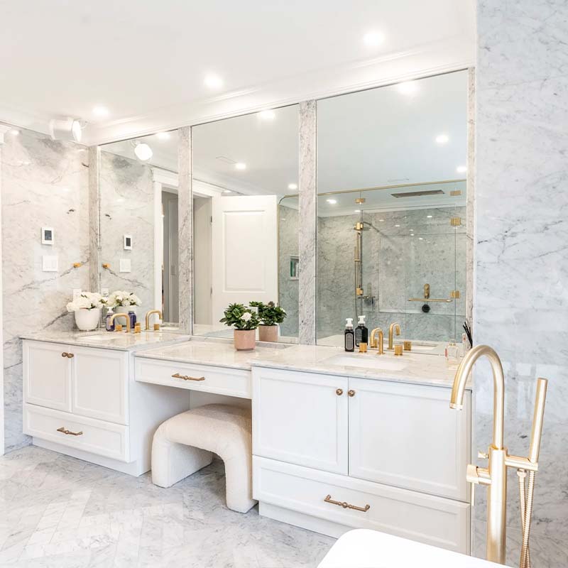 Custom white bathroom with gold handles, marble countertop and triple mirrors by Club Cuisine BCBG Laval